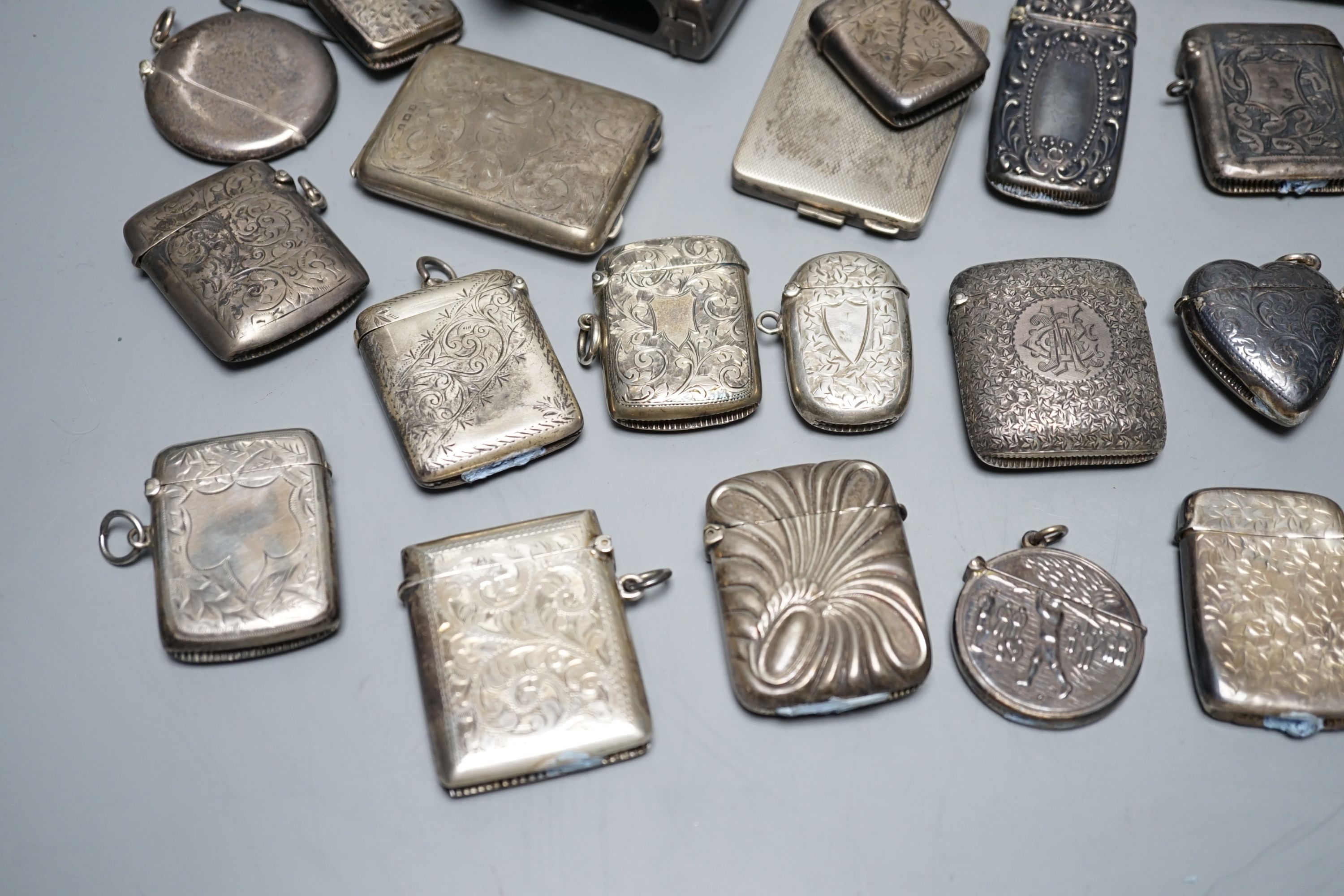 A collection of twenty six assorted mainly early 20th century silver or white metal vesta cases, including heart shape and combination vesta and cheroot cutter, largest 61mm and and seven assorted match cases or sleeves.